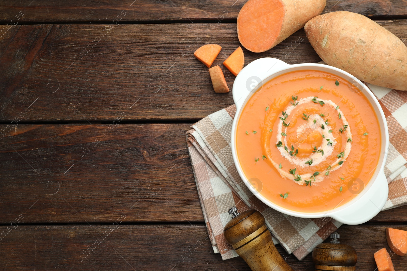 Photo of Delicious sweet potato soup with microgreens and fresh vegetables on wooden table, flat lay. Space for text