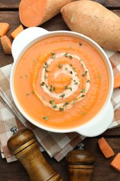 Photo of Delicious sweet potato soup with microgreens and fresh vegetables on wooden table, flat lay