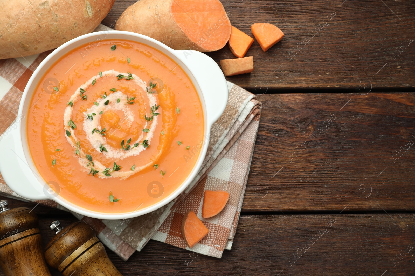 Photo of Delicious sweet potato soup with microgreens and fresh vegetables on wooden table, flat lay. Space for text