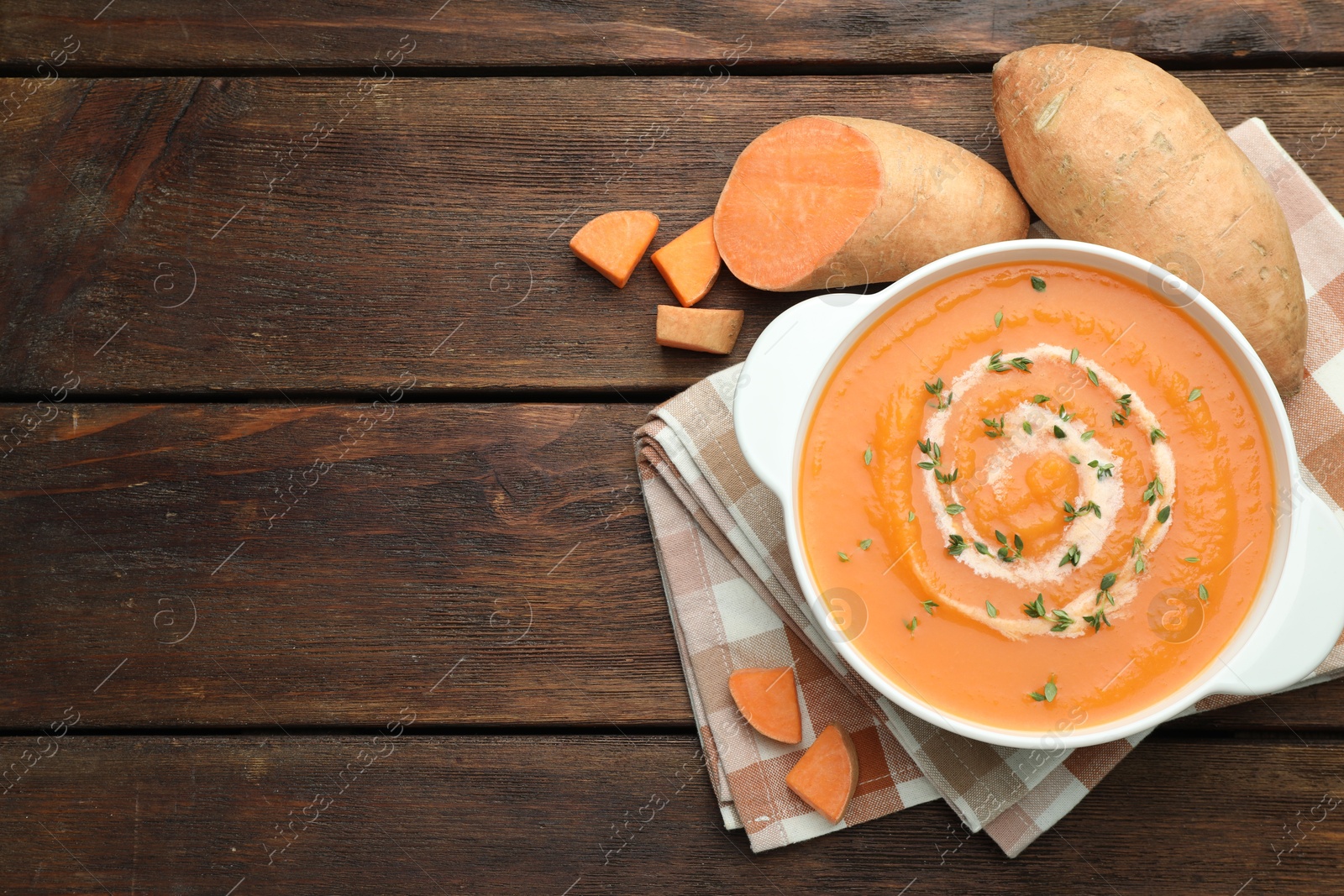 Photo of Delicious sweet potato soup with microgreens and fresh vegetables on wooden table, flat lay. Space for text