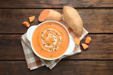 Photo of Delicious sweet potato soup with microgreens and fresh vegetables on wooden table, flat lay