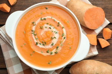 Photo of Delicious sweet potato soup with microgreens and fresh vegetables on wooden table, flat lay