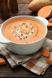 Photo of Delicious sweet potato soup with microgreens and fresh vegetables on wooden table, closeup