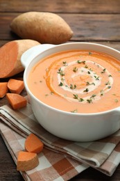 Photo of Delicious sweet potato soup with microgreens and fresh vegetables on wooden table, closeup