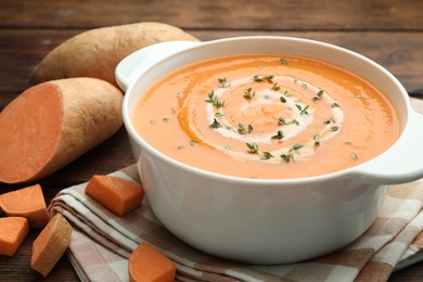 Photo of Delicious sweet potato soup with microgreens and fresh vegetables on wooden table, closeup