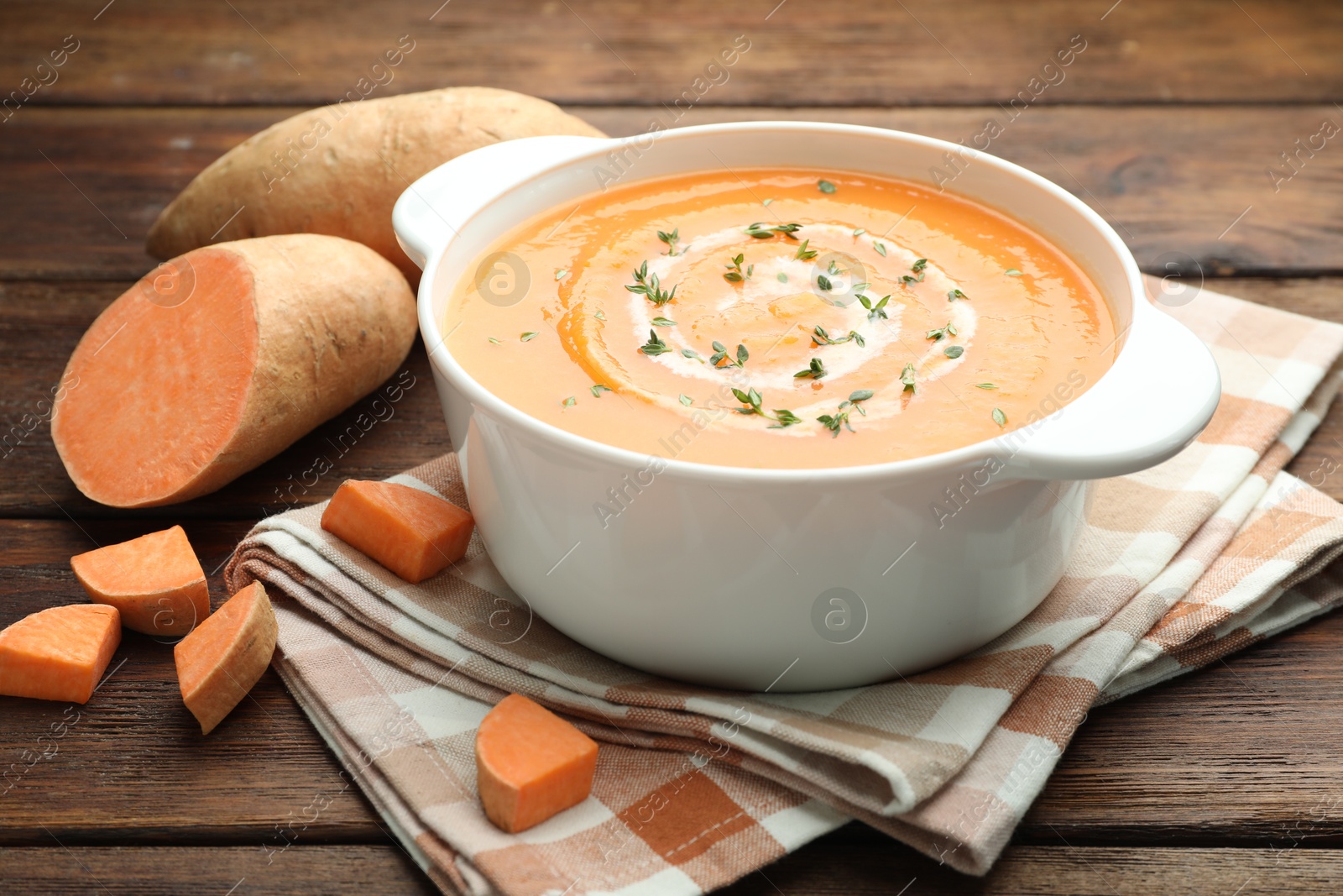 Photo of Delicious sweet potato soup with microgreens and fresh vegetables on wooden table, closeup