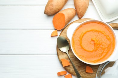 Photo of Delicious sweet potato soup served on white wooden table, flat lay. Space for text