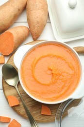 Photo of Delicious sweet potato soup served on white wooden table, flat lay