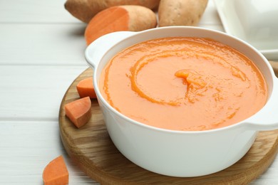 Photo of Delicious sweet potato soup with fresh vegetable on white wooden table, closeup