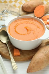 Photo of Delicious sweet potato soup served on white wooden table