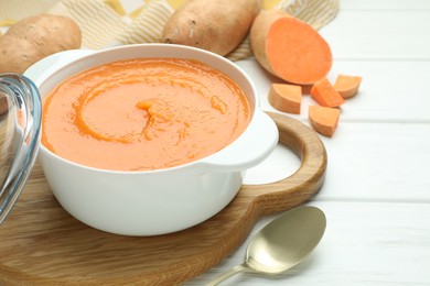 Photo of Delicious sweet potato soup served on white wooden table, closeup