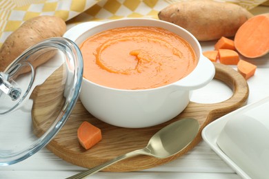 Photo of Delicious sweet potato soup served on white wooden table, closeup