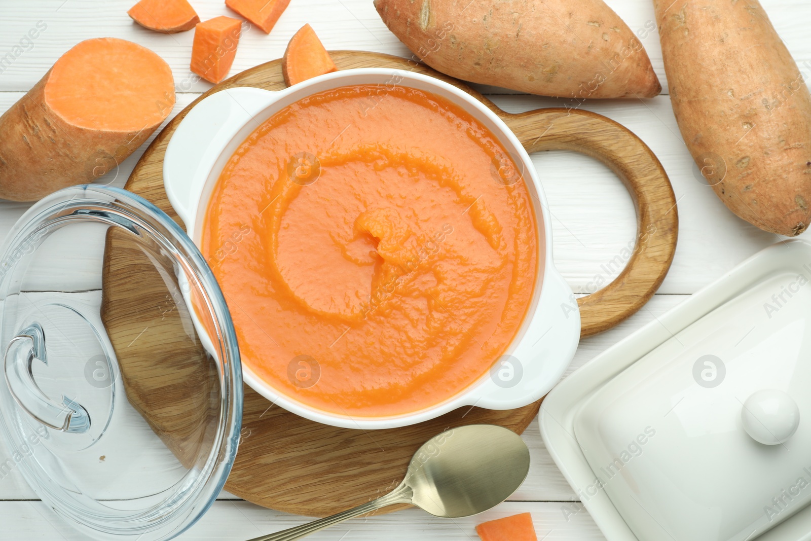 Photo of Delicious sweet potato soup served on white wooden table, flat lay