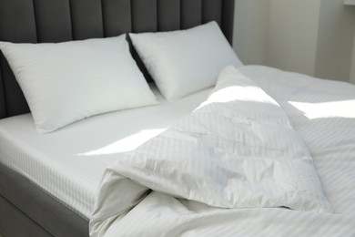 Comfortable bed with clean linens and pillows indoors