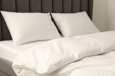 Photo of Comfortable bed with clean linens and pillows indoors, closeup