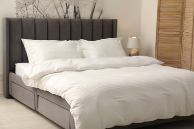 Photo of Comfortable bed with clean linens and pillows indoors