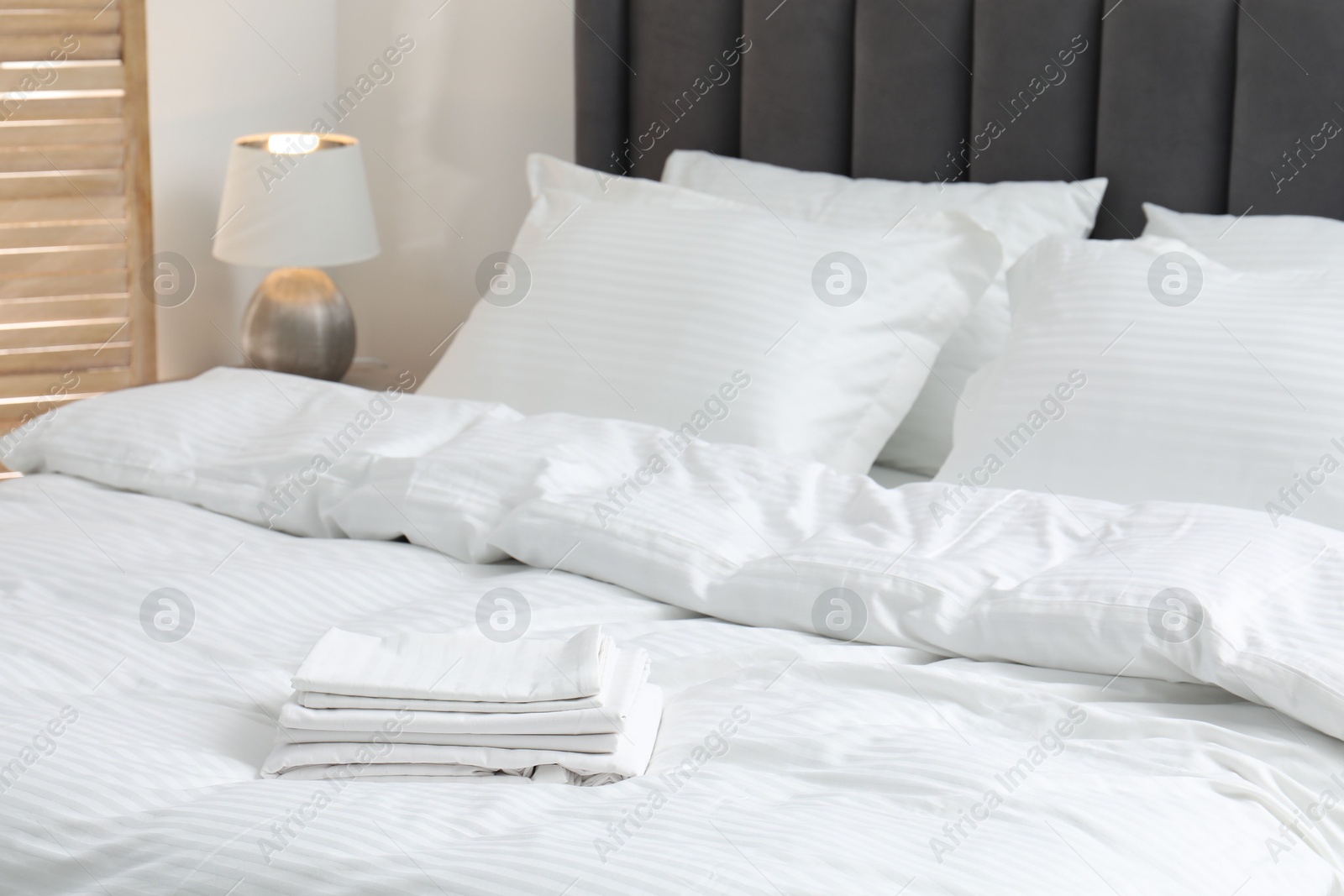 Photo of Comfortable bed with clean linens and pillows indoors