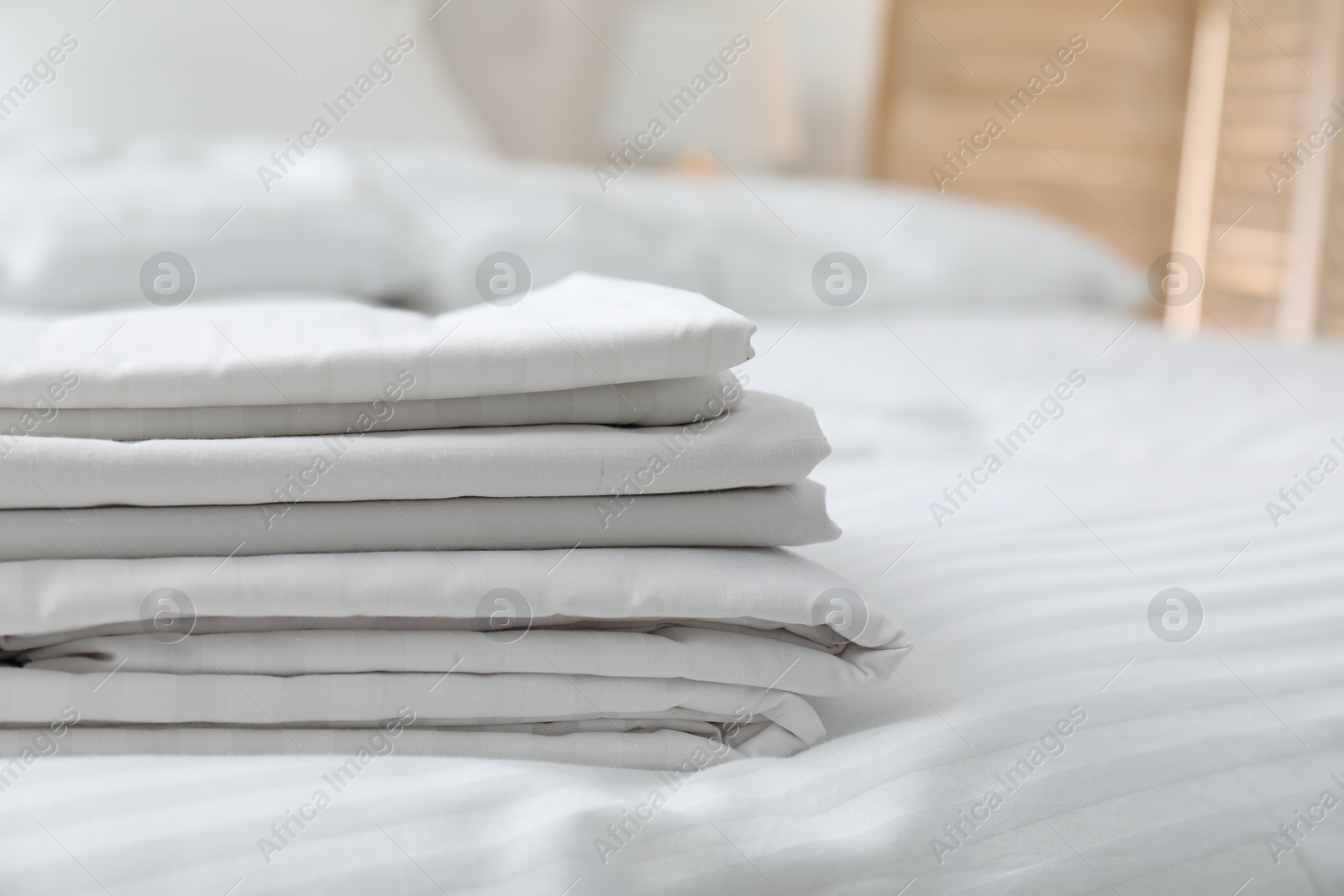 Photo of Stack of clean linens on bed indoors, closeup