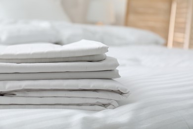 Stack of clean linens on bed indoors, closeup