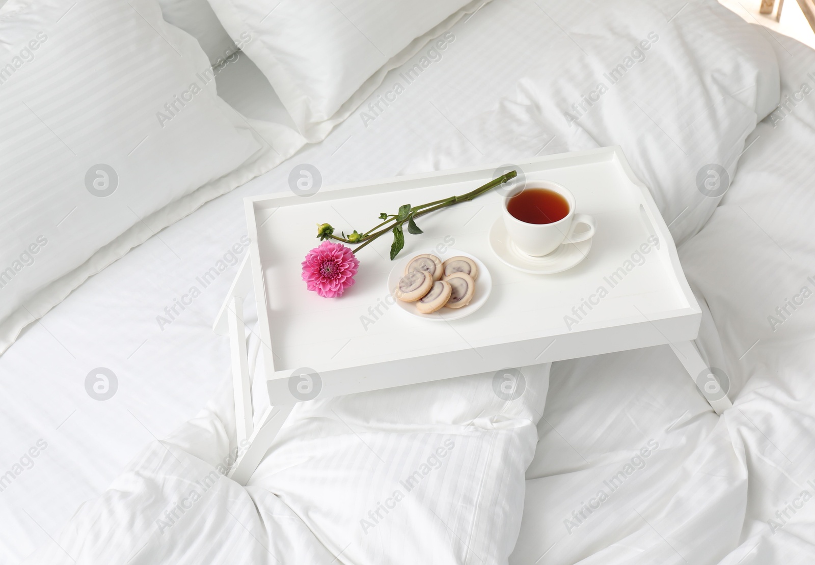 Photo of Breakfast tray on bed with beautiful linens indoors