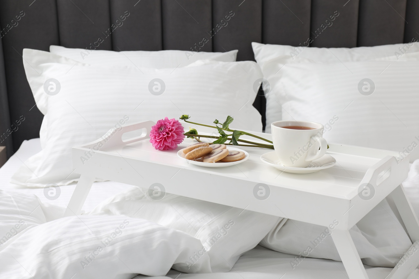 Photo of Breakfast tray on bed with beautiful linens indoors