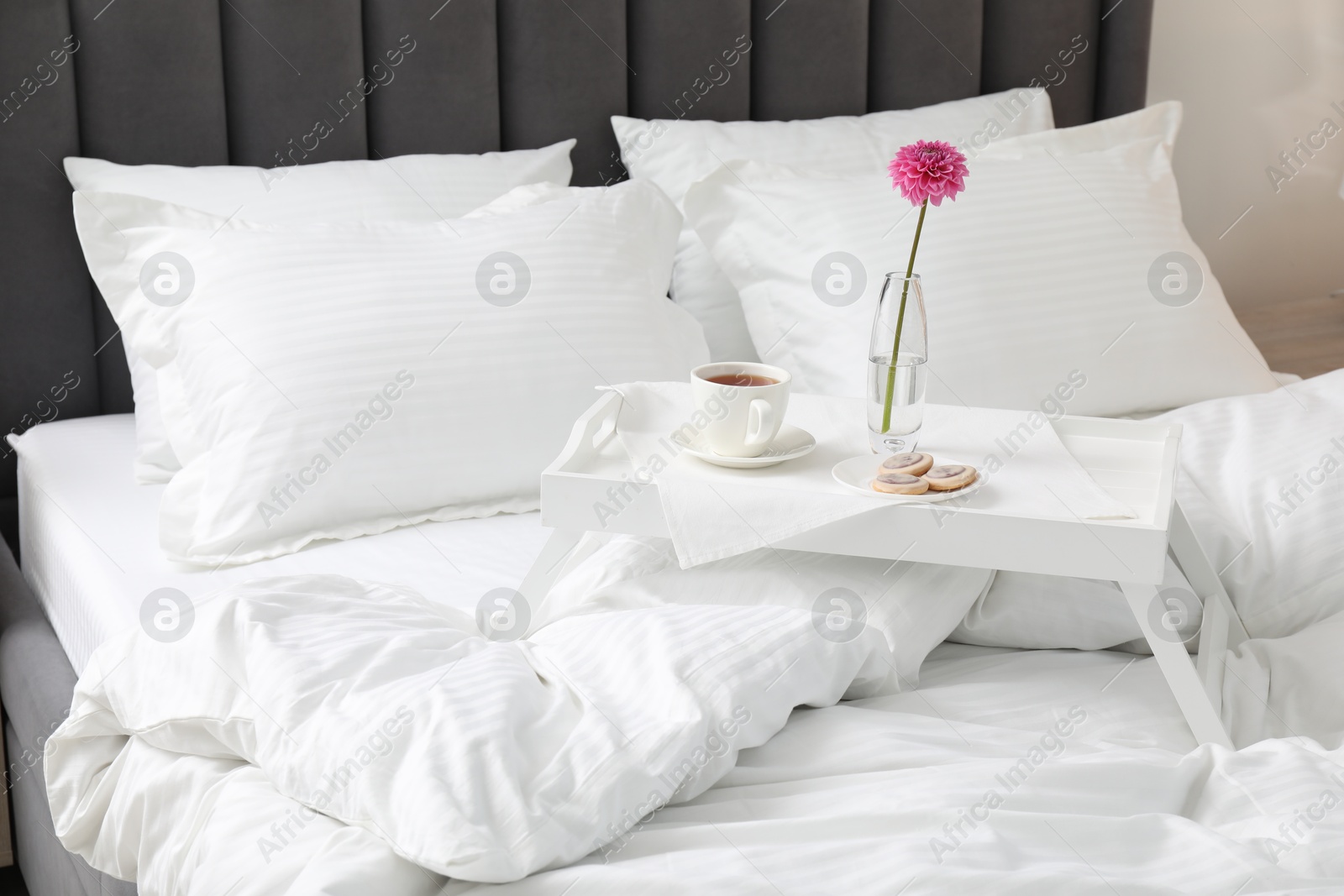 Photo of Breakfast tray on bed with beautiful linens indoors