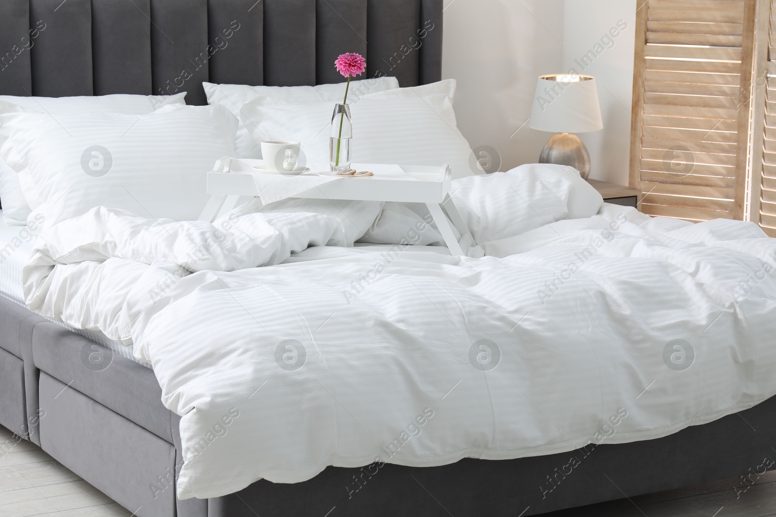 Photo of Breakfast tray on bed with beautiful linens indoors