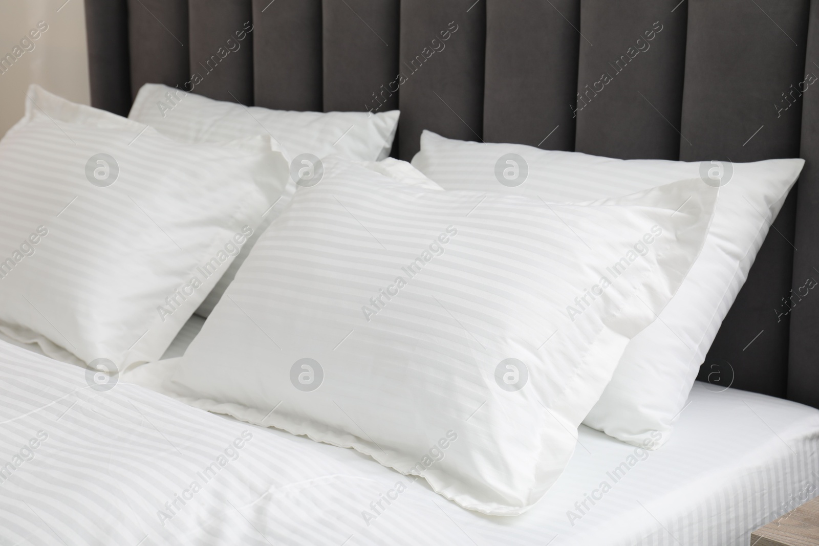 Photo of Comfortable bed with clean linens and pillows indoors