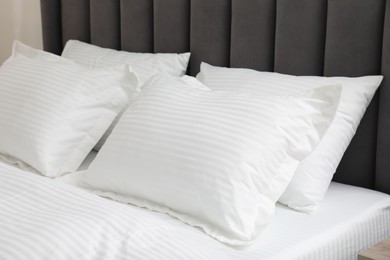 Comfortable bed with clean linens and pillows indoors