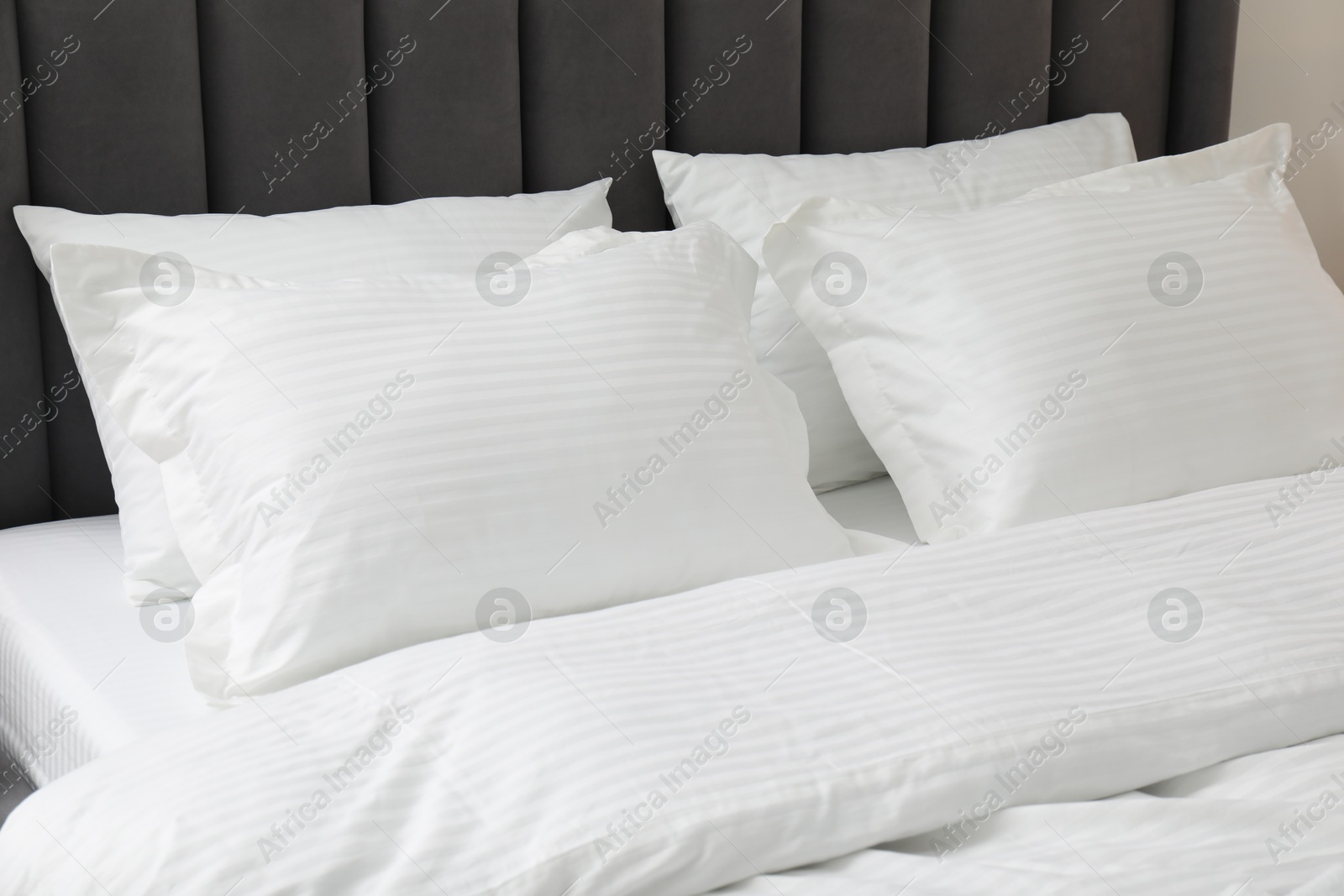 Photo of Comfortable bed with clean linens and pillows indoors