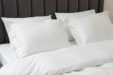 Comfortable bed with clean linens and pillows indoors