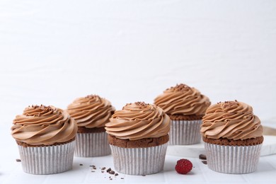 Photo of Tasty cupcakes with chocolate cream on white tiled table, space for text