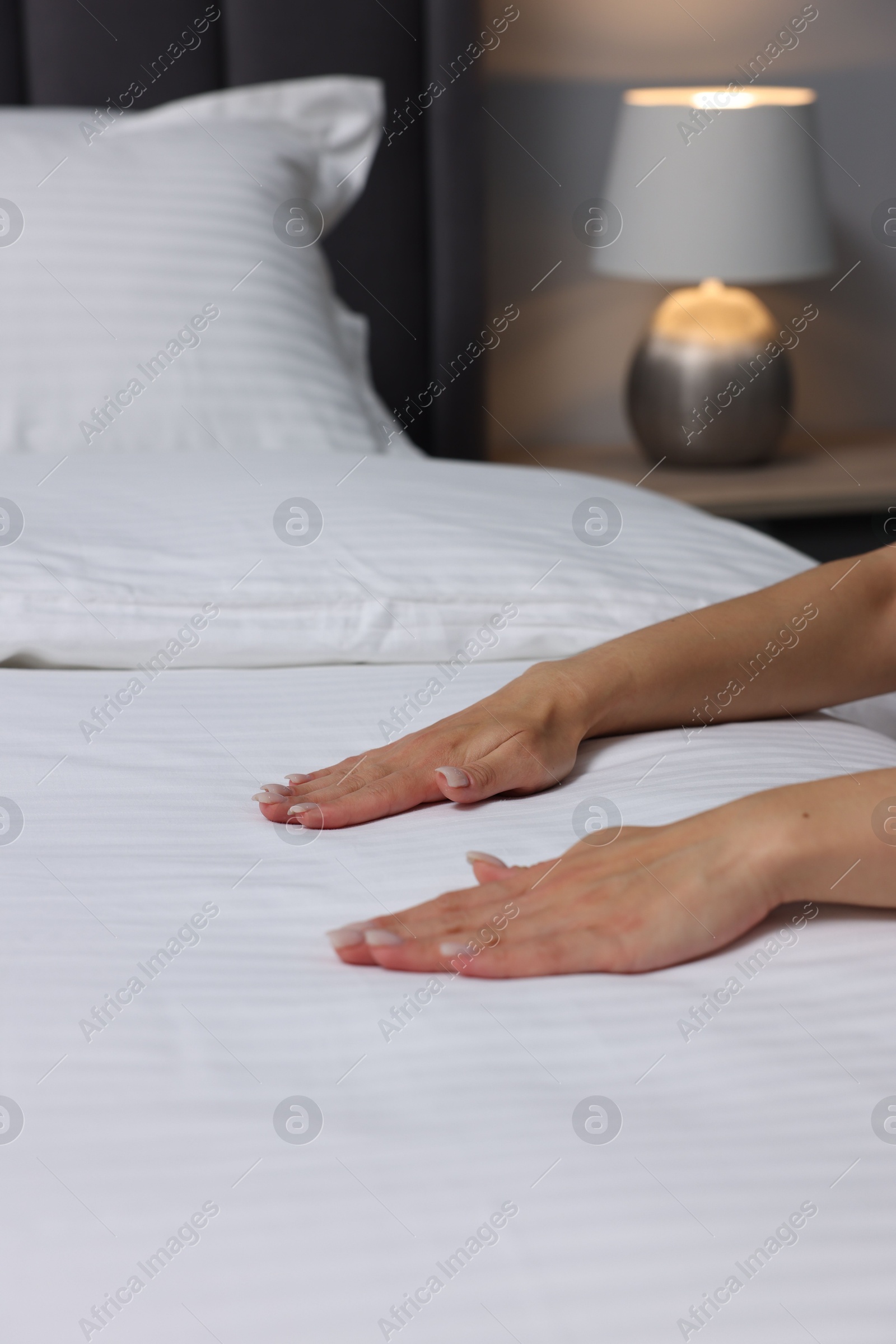 Photo of Woman changing clean bed linens at home, closeup