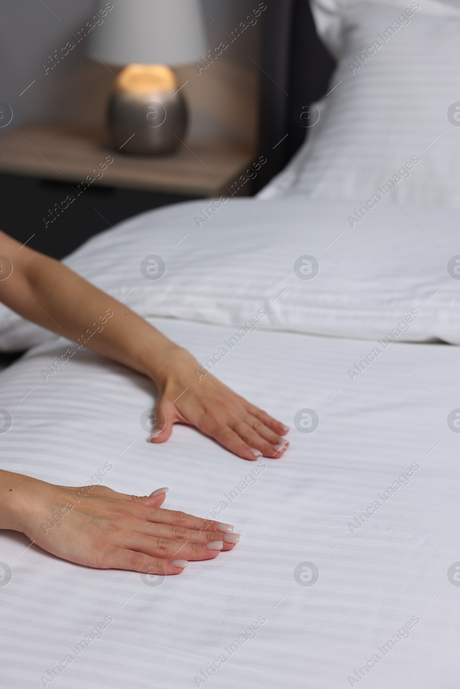 Photo of Woman changing clean bed linens at home, closeup