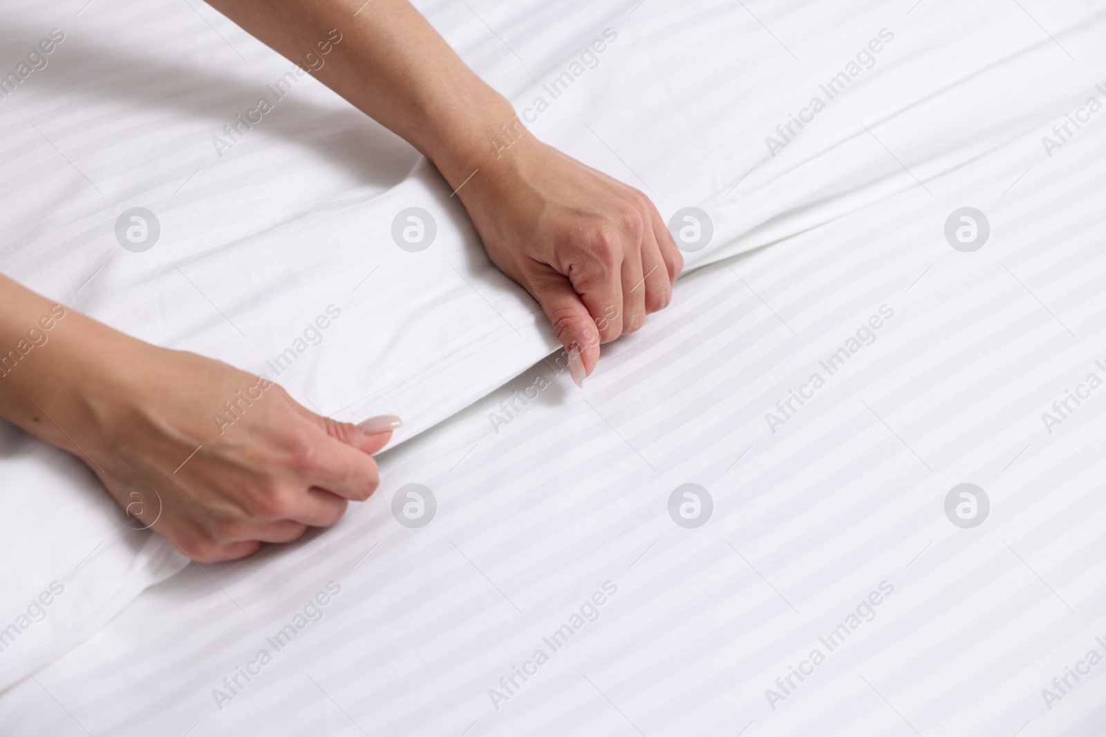 Photo of Woman changing clean bed linens at home, closeup