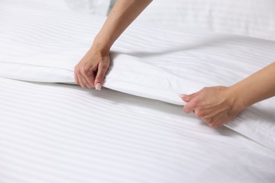 Woman changing clean bed linens at home, closeup