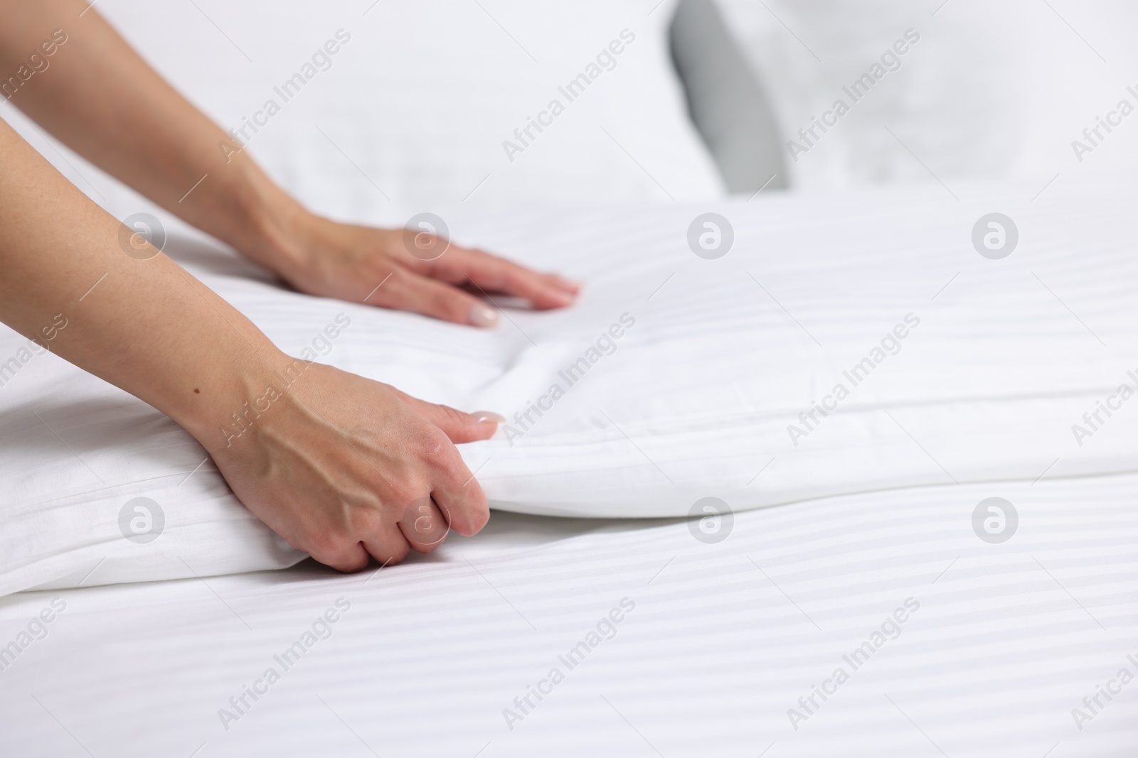 Photo of Woman changing clean bed linens at home, closeup