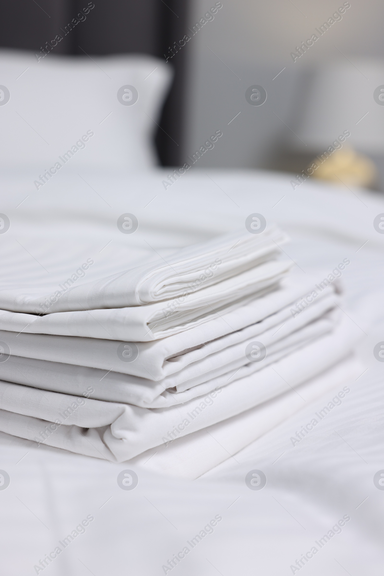 Photo of Stack of clean linens on bed indoors, closeup