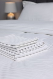 Stack of clean linens on bed indoors