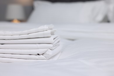 Stack of clean linens on bed indoors, closeup. Space for text