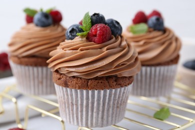 Photo of Tasty cupcakes with chocolate cream and berries on white table, closeup