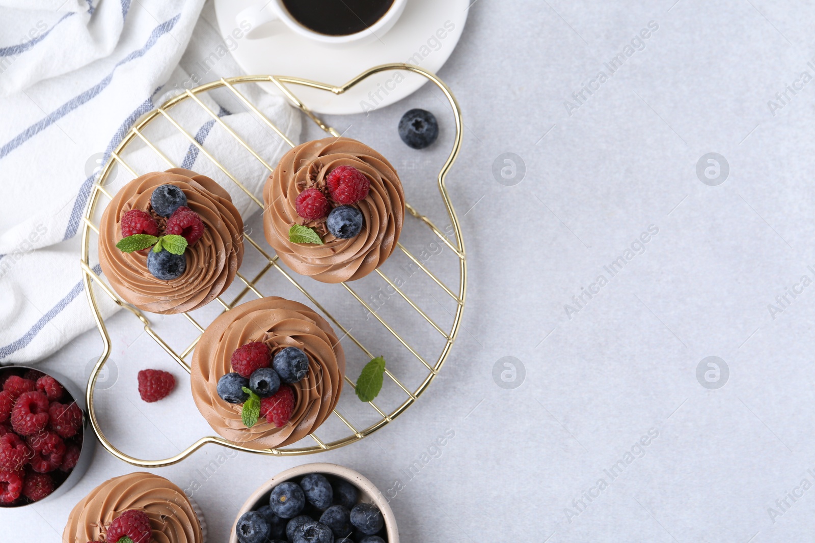 Photo of Tasty cupcakes with chocolate cream and berries on white table, flat lay. Space for text