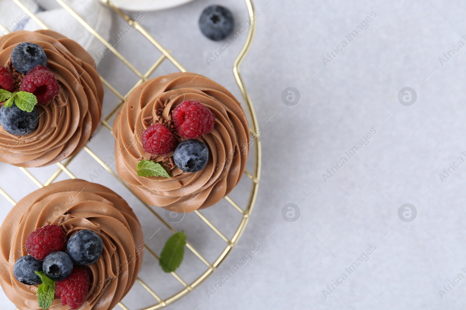 Photo of Tasty cupcakes with chocolate cream and berries on white table, flat lay. Space for text