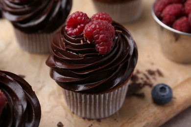 Photo of Tasty cupcakes with chocolate cream and berries on brown table, closeup