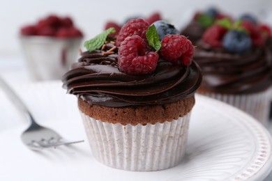 Photo of Tasty cupcakes with chocolate cream and berries on table, closeup