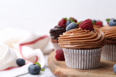 Photo of Tasty cupcakes with chocolate cream and berries on table, closeup. Space for text