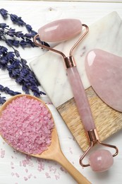 Photo of Face roller, gua sha tool, sea salt and lavender flowers on white wooden background, flat lay