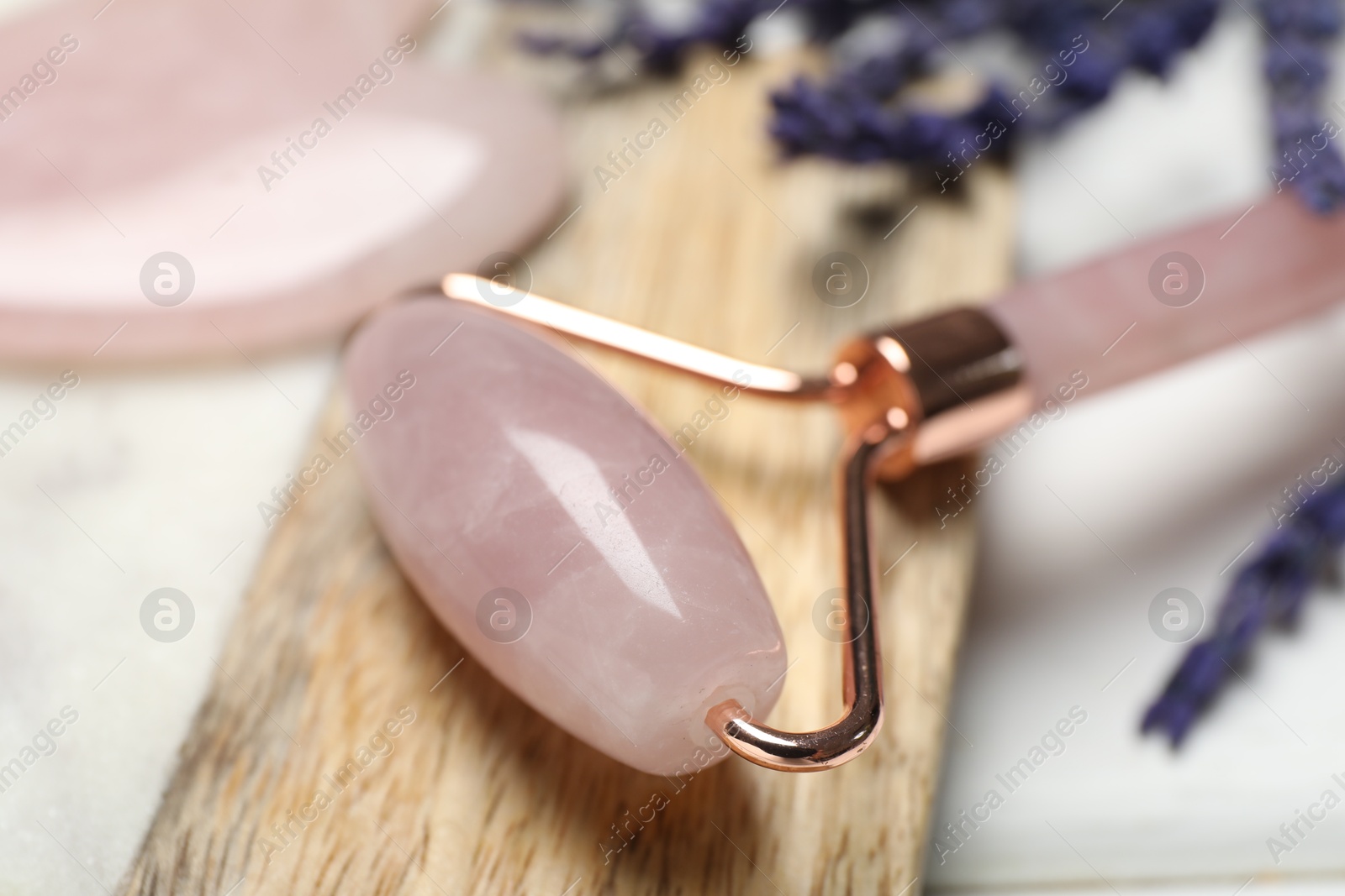 Photo of Rose quartz face roller on light background, closeup