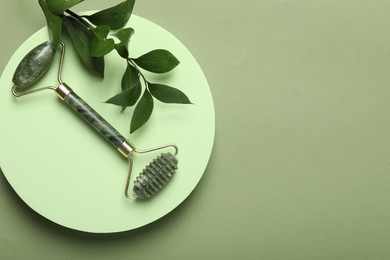 Photo of Face roller and ruscus branch on green background, top view. Space for text