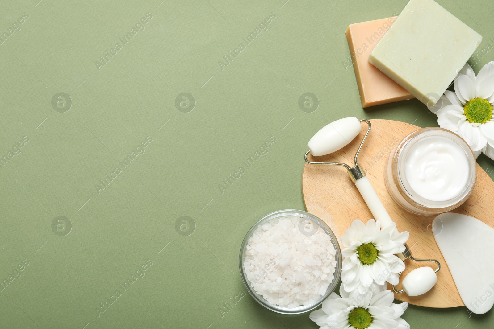 Photo of Flat lay composition with face roller and gua sha tool on green background, space for text